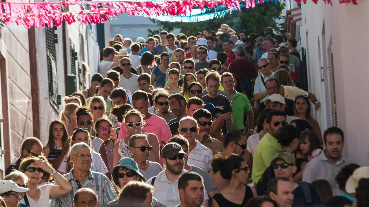 Ve&iuml;ns i visitants d&rsquo;Es Mercadal baixant pels carrers del poble durant les festes de Sant Mart&iacute;.
Foto: Jez Timms